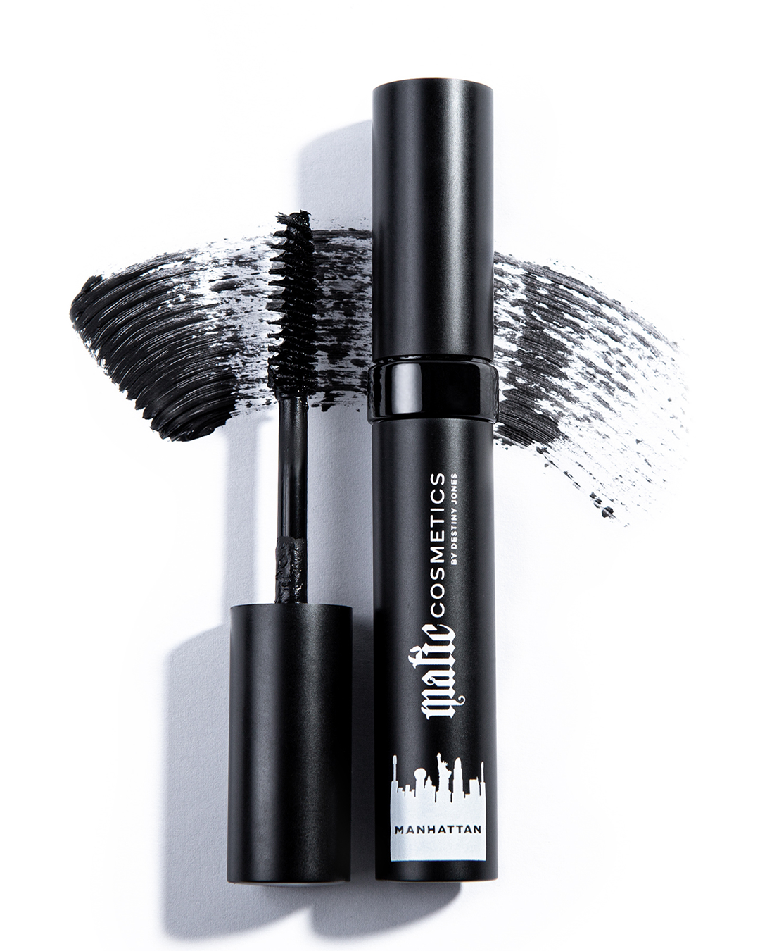 A tube of Manhattan HD Lashes Mascara with the wand applicator showing the product in use, creating a dramatic lash effect.